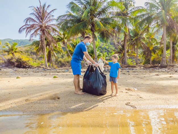 Jeunes militants familiaux heureux ramassant des déchets plastiques sur la plage Papa et fils bénévoles nettoient les ordures Problèmes de pollution de l'environnement Loisirs de plein air Éducation naturelle des enfants