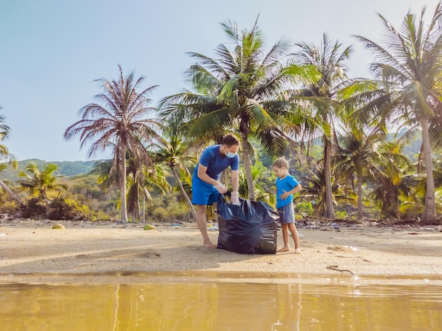 Jeunes militants familiaux heureux ramassant des déchets plastiques sur la plage Papa et fils bénévoles nettoient les ordures Problèmes de pollution de l'environnement Loisirs de plein air Éducation naturelle des enfants