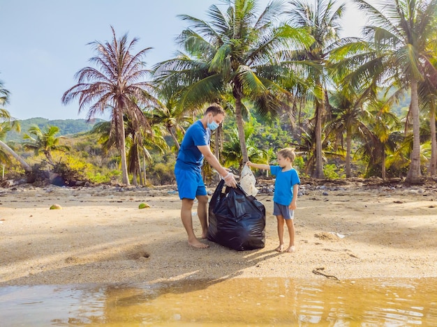 Jeunes militants familiaux heureux ramassant des déchets plastiques sur la plage Papa et fils bénévoles nettoient les ordures Problèmes de pollution de l'environnement Loisirs de plein air Éducation naturelle des enfants