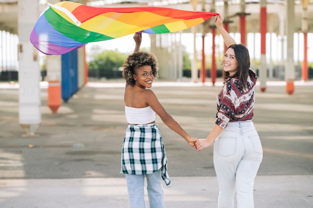 Jeunes militants souriants et tenant le drapeau arc-en-ciel symbole du mouvement social LGBTI