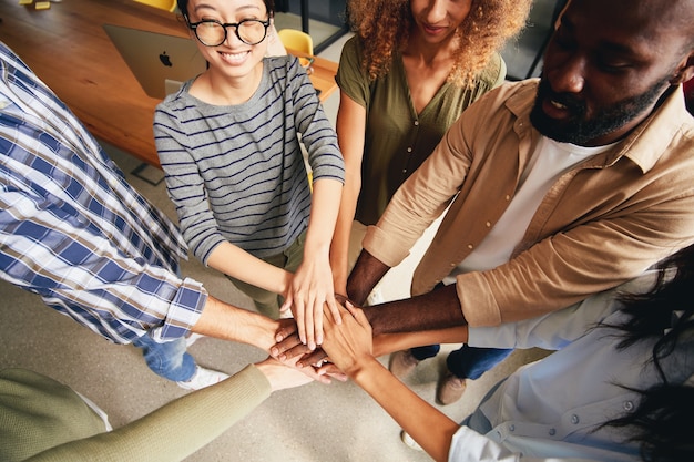 Photo jeunes multiraciaux mettant les mains ensemble pour l'esprit d'équipe