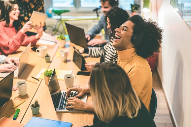 Jeunes multiraciaux s'amusant à travailler à l'intérieur d'un bureau de coworking - Focus african man face