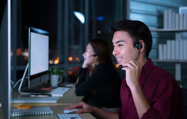 Les jeunes opérateurs de services à la clientèle asiatiques thaïlandais travaillant de nuit dans un centre d'appels