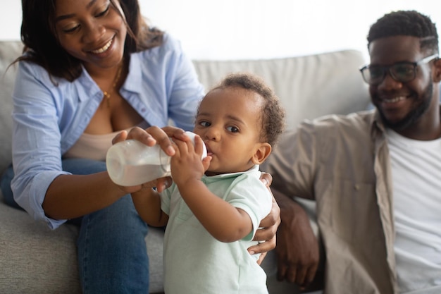Jeunes parents afro-américains nourrissant un enfant à la bouteille