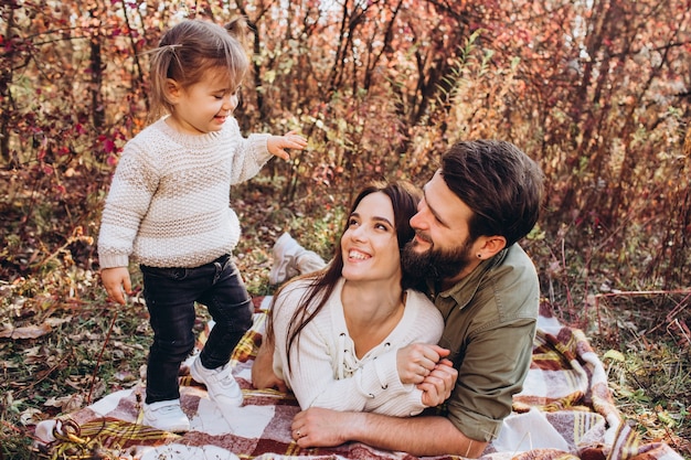 Jeunes parents avec fille marchent dans le parc automne