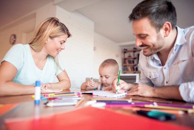 Photo les jeunes parents avec un jeune enfant dessinent