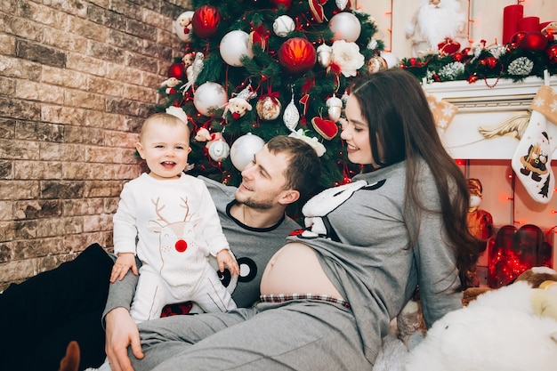 Jeunes parents avec jeune fils près de l'arbre de Noël