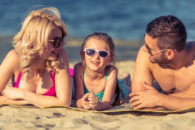 Jeunes parents et leur fille sur la plage.