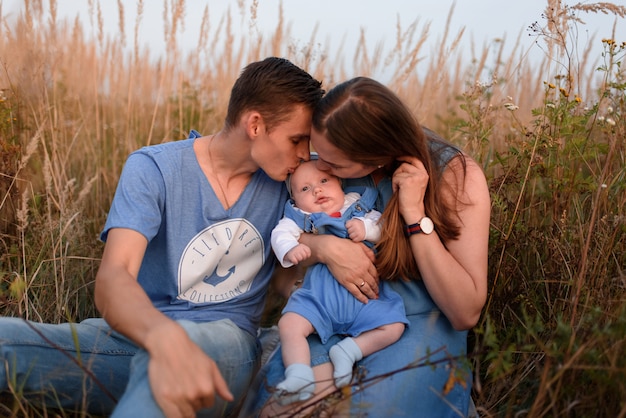 Les jeunes parents marchent avec leur petit fils sur le terrain