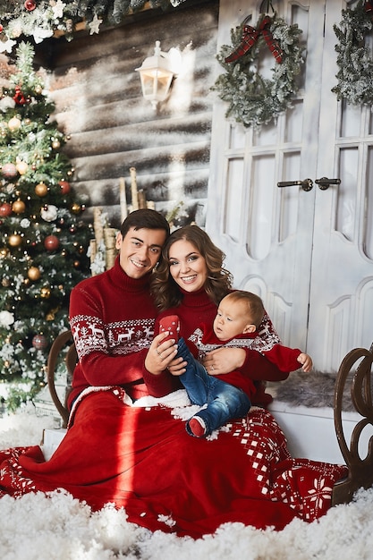 Les jeunes parents et le petit garçon s'amusent ensemble à l'intérieur décoré pour Noël.