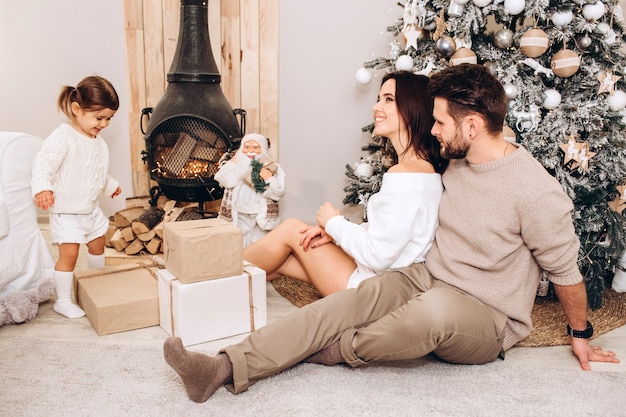 Jeunes parents avec une petite fille près de l'arbre de Noël