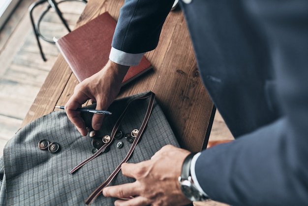 Jeunes perfectionnistes. Bouchent la vue de dessus du créateur de mode choisissant un échantillon de tissu