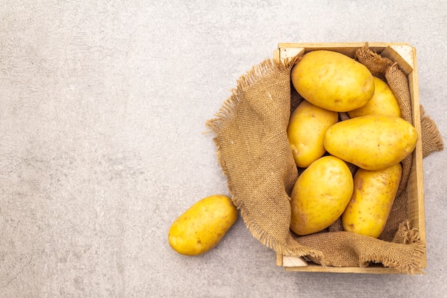 Jeunes pommes de terre crues non pelées dans une caisse en bois