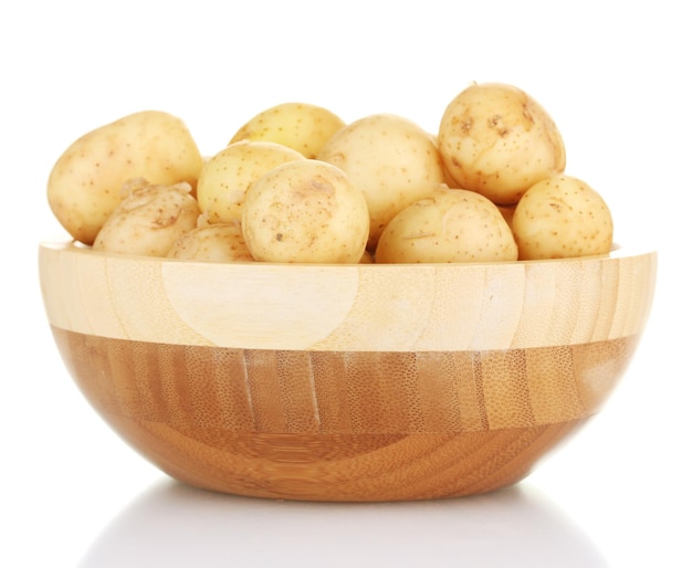 Jeunes pommes de terre dans un bol en bois isolé sur blanc