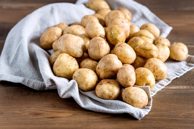 Jeunes pommes de terre précoces dans un vieux petit seau en aluminium sur un fond de bois