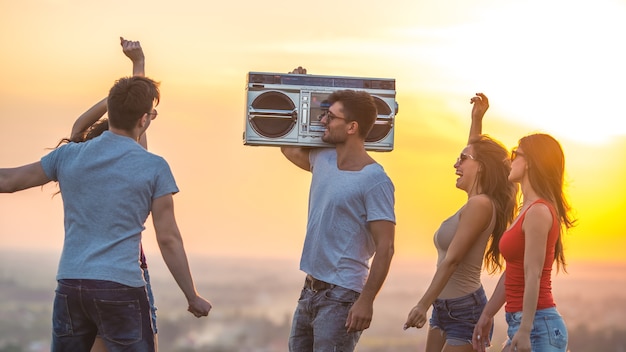 Les jeunes qui dansent avec une boom box sur fond de coucher de soleil