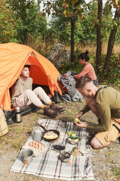 Jeunes randonneurs déballant leur sac et préparant de la nourriture à l'arrêt du déjeuner en forêt