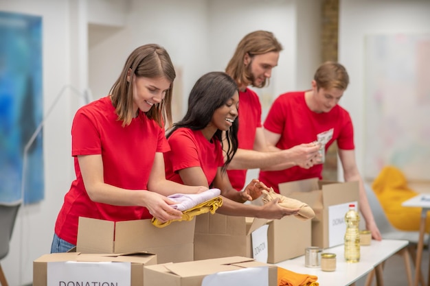 Jeunes en rouge emballant les cartons avec l'aide humanitaire