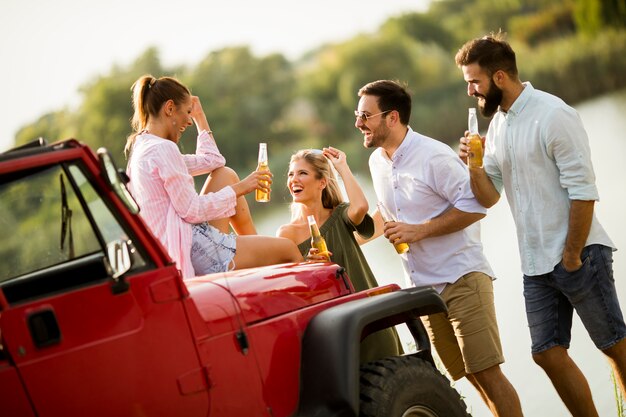 Photo jeunes s'amusant en voiture décapotable au bord d'une rivière