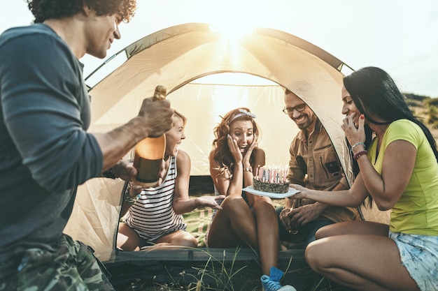 Les jeunes s'amusent bien au camp dans la nature. Ils célèbrent un anniversaire, rient et saluent leur ami avec un gâteau d'anniversaire, heureux d'être ensemble.