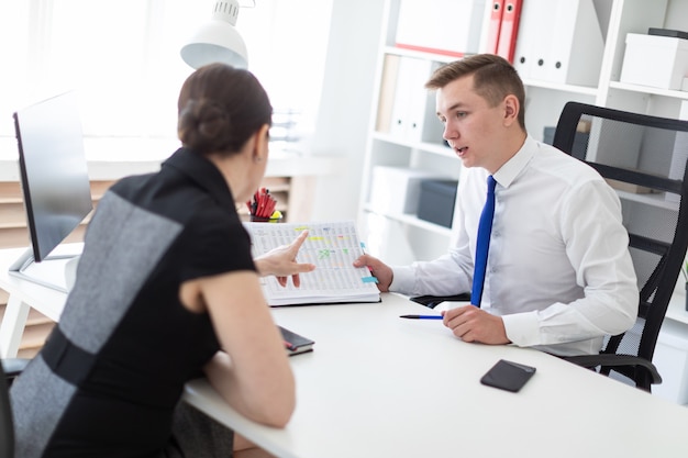 Les jeunes sont assis au bureau à la table d’ordinateur et travaillent avec des documents.