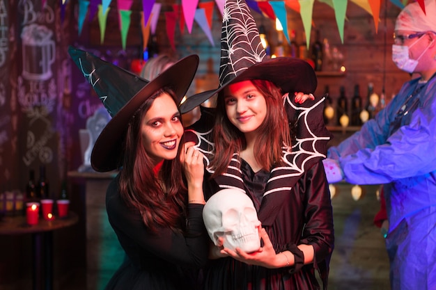 Jeunes sorcières séduisantes regardant la caméra à la fête d'halloween. Sorcières célébrant l'amitié.