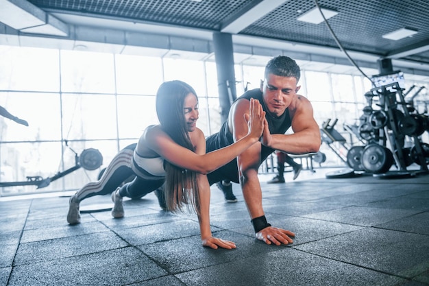 Jeunes sportifs faisant des pompes ensemble dans la salle de sport