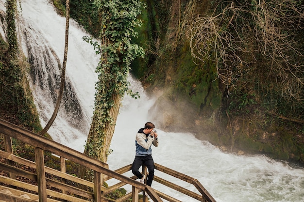 Les jeunes touristes élégants photographient la cascade.