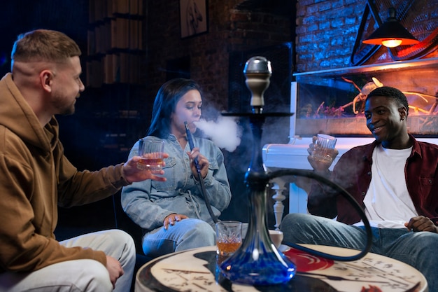 Photo les jeunes vapotant d'un narguilé dans un bar