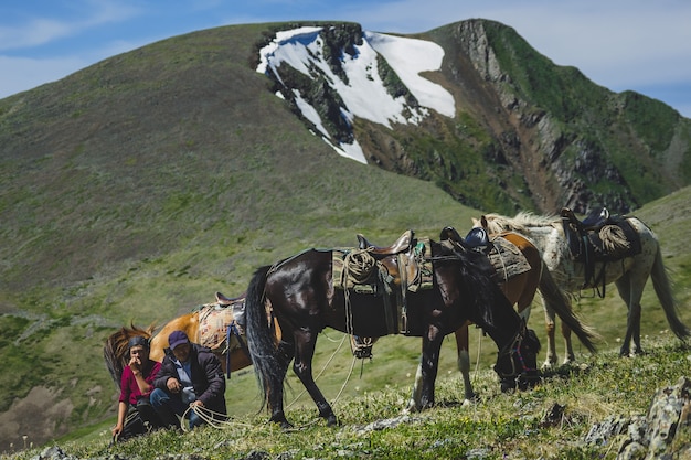 Jeunes et vieux cavaliers à pied trois chevaux à flanc de montagne dans le district d'Ulagansky de la République de l'Altaï, Russie