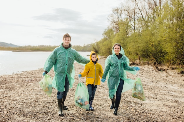 Jeunes volontaires avec des sacs à ordures. Écologie. Jeune famille sur la nature.