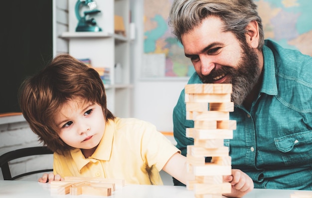 Jeux éducatifs père souriant et fils concentré jouant au jeu jenga à la maison