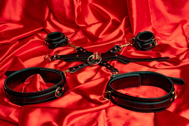 Jeux de sexe pour adultes Articles BDSM Lanières de cuir menottes collier sur une feuille de satin rouge