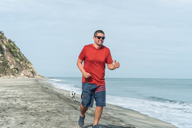 Un joggeur courant le long d'une plage avec son chien