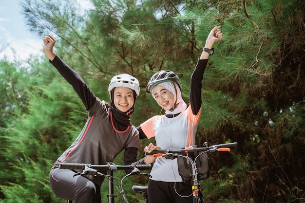 Joie de deux filles voilées avec les mains serrées en faisant du vélo