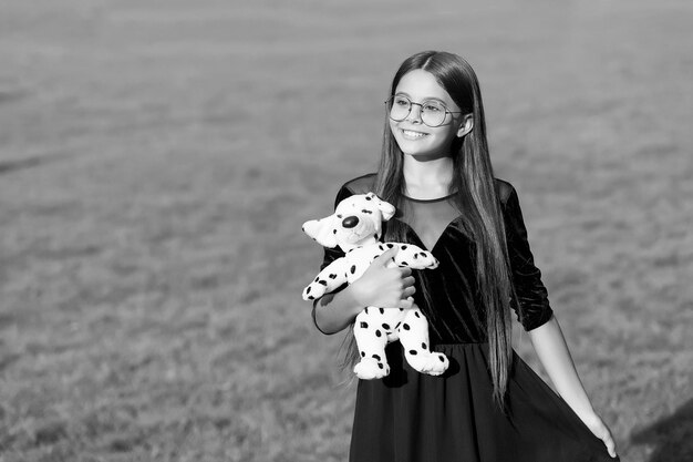 La joie des meilleures choses Un enfant heureux tient un chien jouet sur l'herbe verte Animal de compagnie Amis et amitié Jouer à des jeux Garde d'enfants et enfance Espace de copie de la journée internationale des enfants