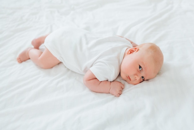 Joli bébé de 2 mois allongé sur le lit linge de lit naturel peau de bébé délicate
