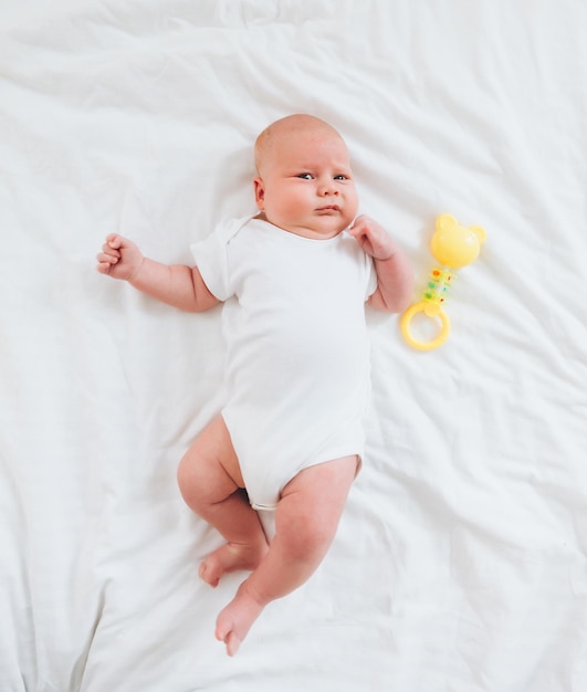 Joli bébé de 2 mois allongé sur le lit linge de lit naturel peau de bébé délicate