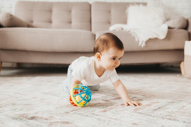 Joli bébé de 9 mois jouant avec un ballon coloré dans une pépinière avec des meubles blancs