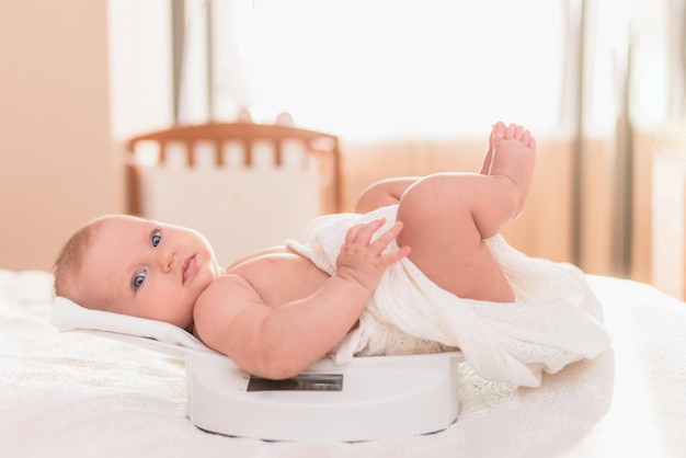 Joli bébé allongé sur une balance électronique dans sa chambre