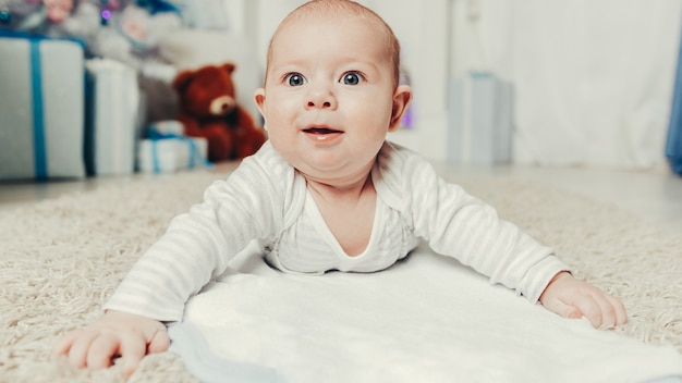 Joli bébé allongé sur le tapis dans le salon cosy. le concept de Noël