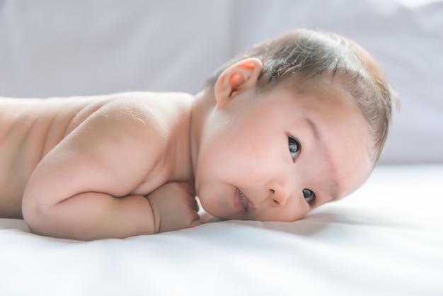 Joli bébé asiatique allongé sur le lit sous l'angle avant