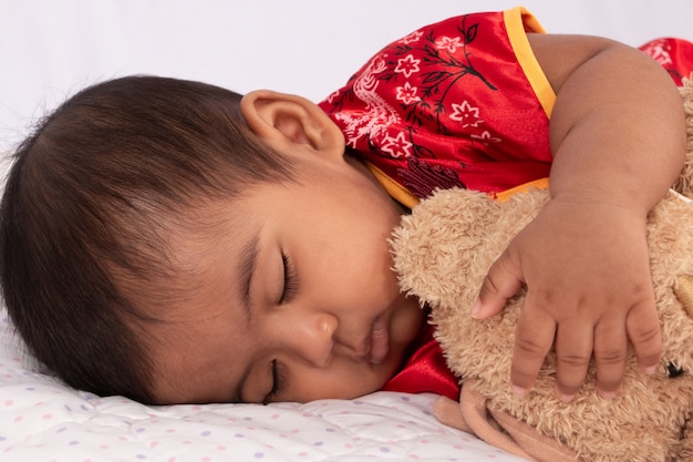 Joli bébé asiatique en robe rouge traditionnelle chinoise dormant