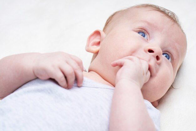 Joli bébé aux yeux bleus suce les doigts