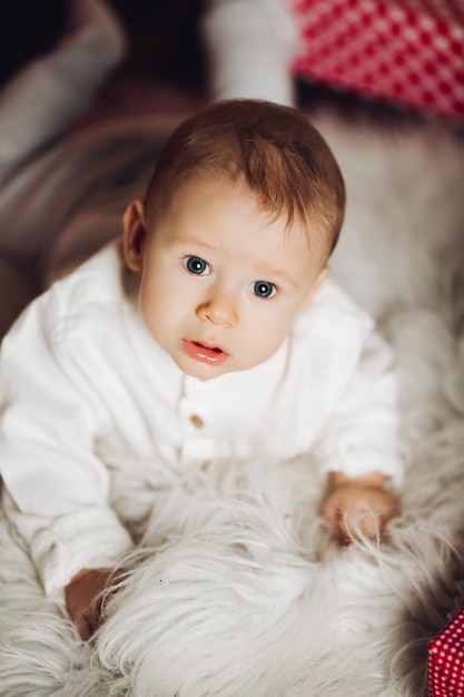 Photo joli bébé en blanc avec des cadeaux de noël.