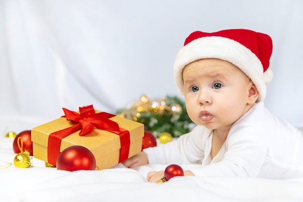 Joli bébé avec bonnet de noel jouant avec la décoration de Noël