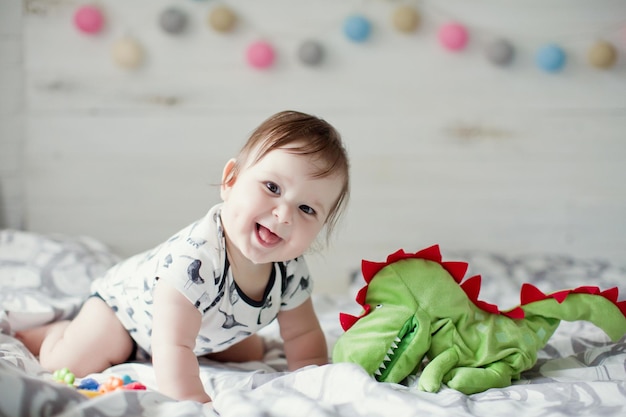 Joli bébé caucasien dans un drap blanc jouant sur le lit