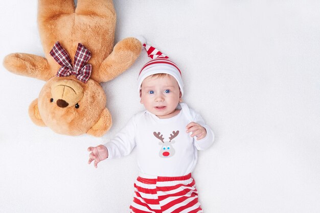 Joli bébé en costume de père Noël et gros ours en peluche