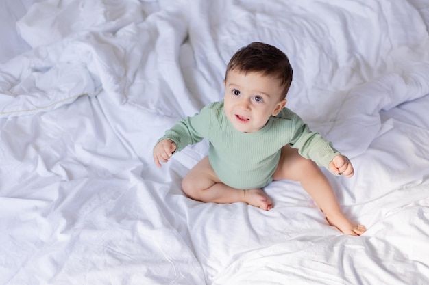 Joli bébé dans un body en coton est allongé sur le lit à la maison