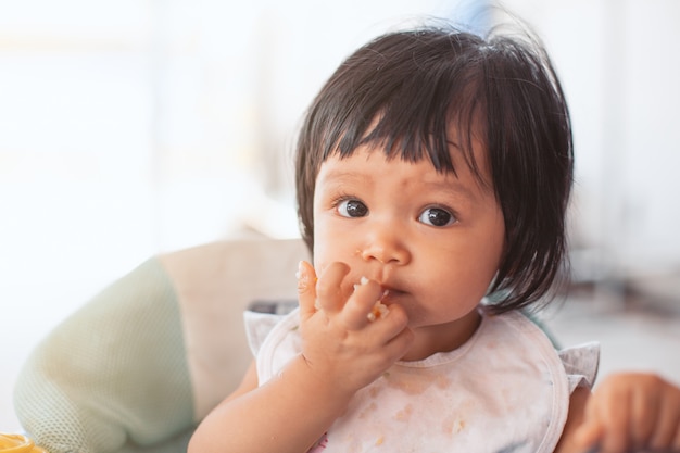 Joli bébé enfant asiatique fille manger des aliments sains par elle-même